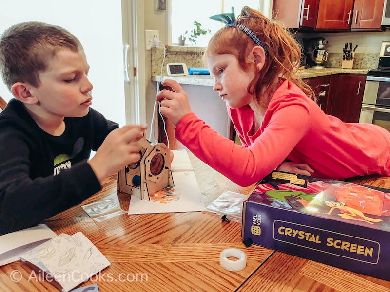 A boy and girl working together to build a crystal screen.