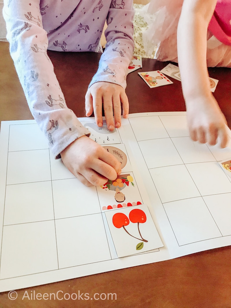 A lap mat with two little girls hands holding the tokens.
