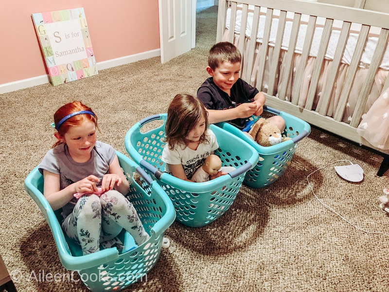 Three kids in blue laundry baskets.