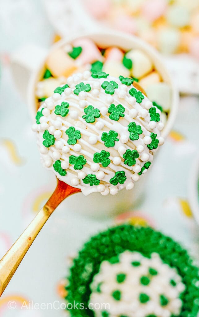 A hot cocoa bomb covered in shamrock sprinkles.