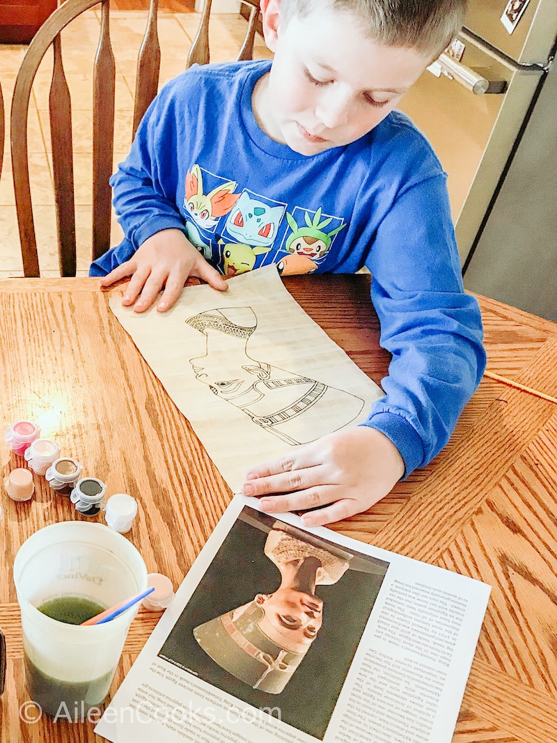 A boy decorating a papyrus scroll.