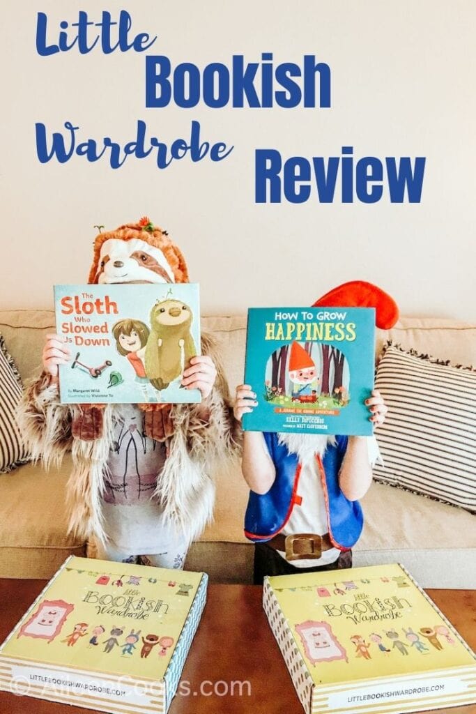 Two girls dressed in costumes and holding children's books in front of their faces with the words "Little Bookish Wardrobe Review" in blue lettering above their heads.