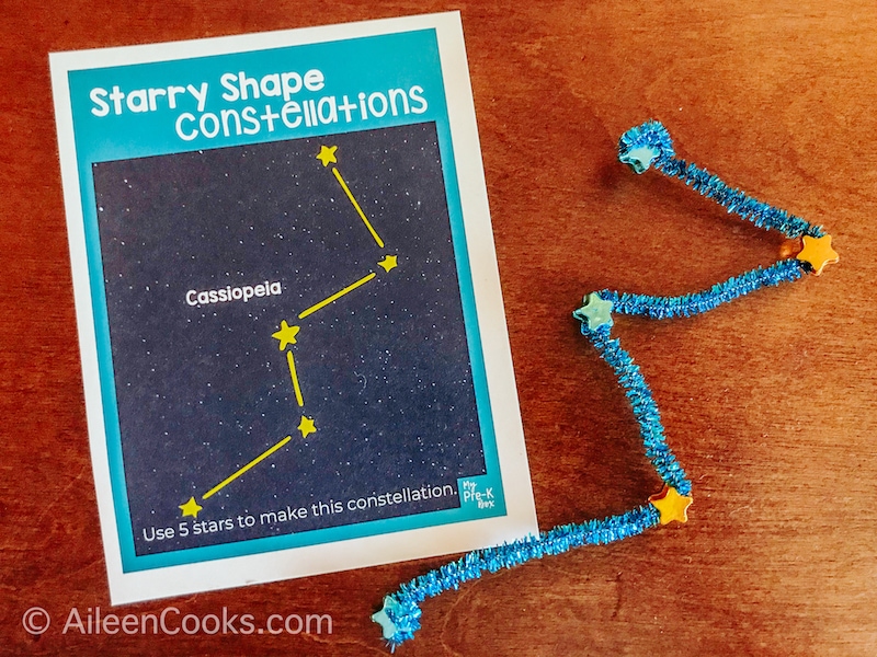 A constellation card next to the constellation built from a pipe cleaner and star-shaped beads. 