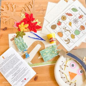 Fall preschool crafts and laminated worksheets laid out on a wooden table.