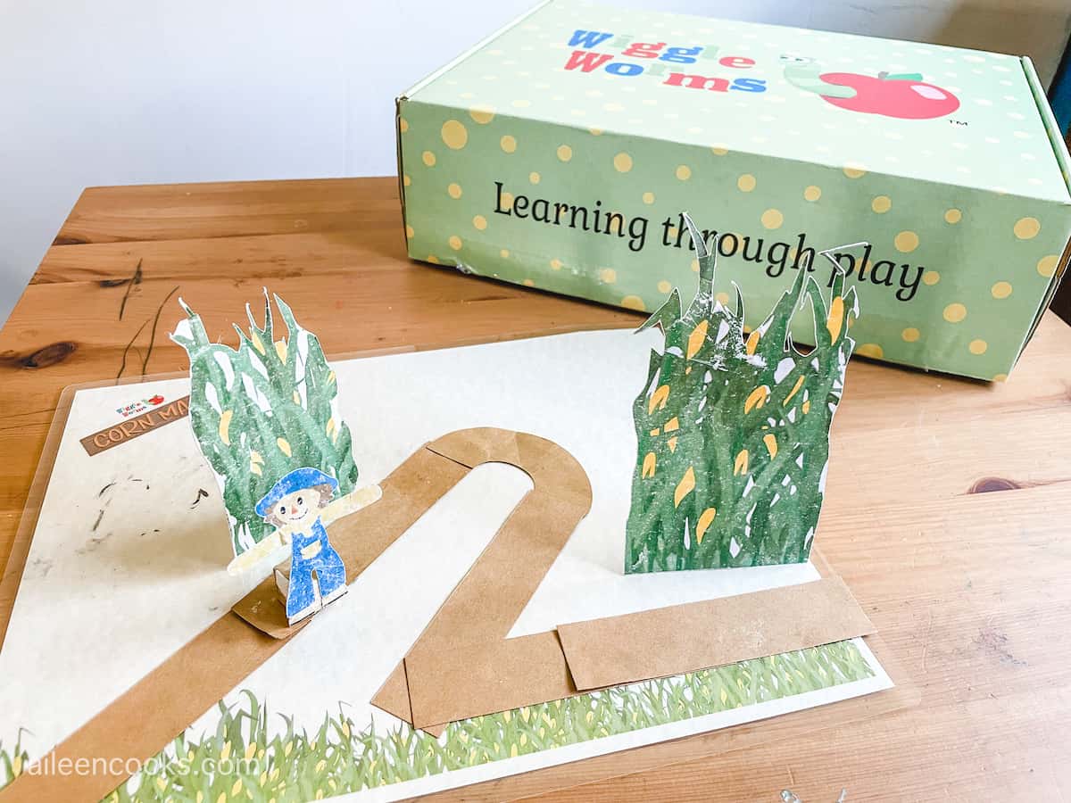 A paper craft corn maze with a small paper scarecrow standing up In the center.
