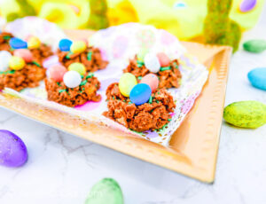 Bird nest cookies on a gold platter with decorative bunnies in the background.
