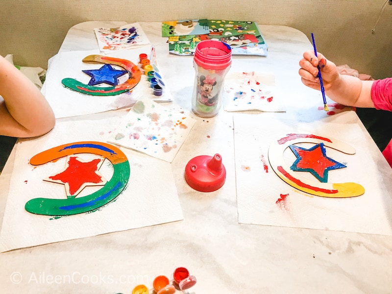 Three kids painting wooden horseshoes.