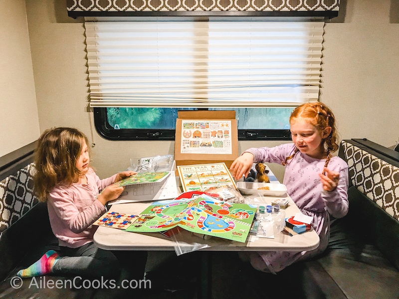 Two girls sitting at a table with an Ivy Kids box opened up in front of them.