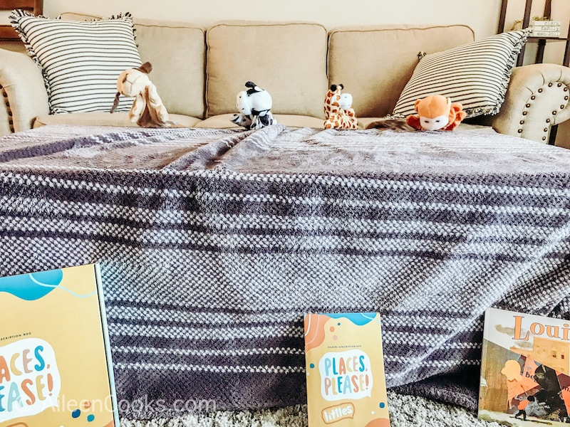 Four animal puppets being held by kids behind a blanket covered table.