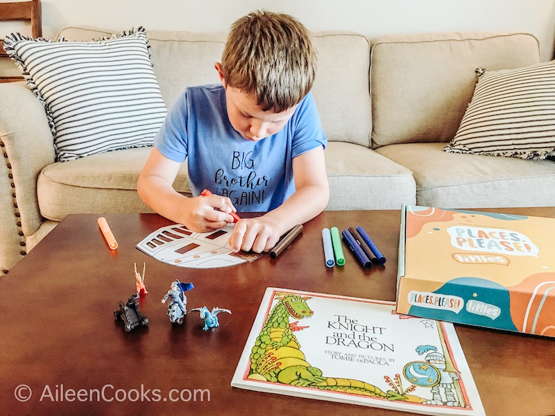 A boy coloring in a knight mask.