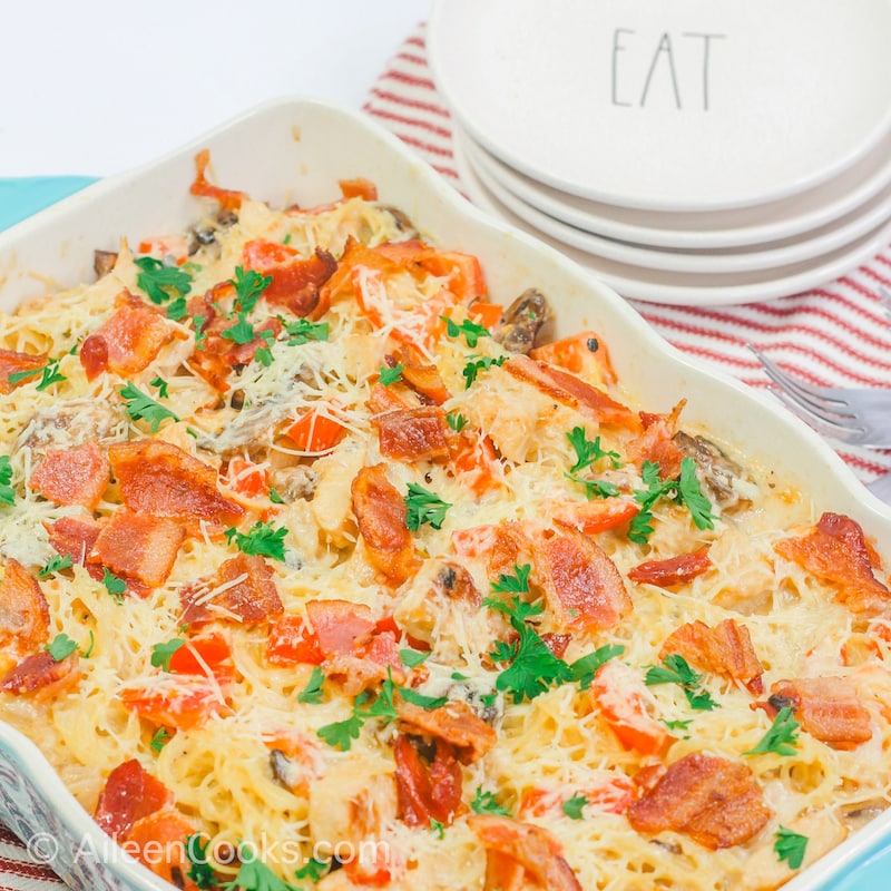 Chicken Caesar pasta topped with fresh chopped parsley in a blue baking dish.