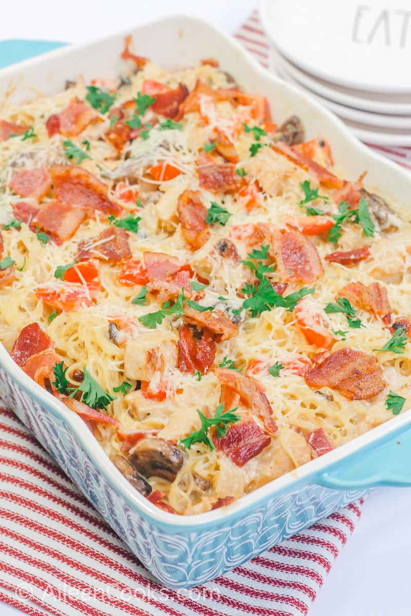 Chicken Caesar pasta topped with fresh chopped parsley in a blue baking dish.