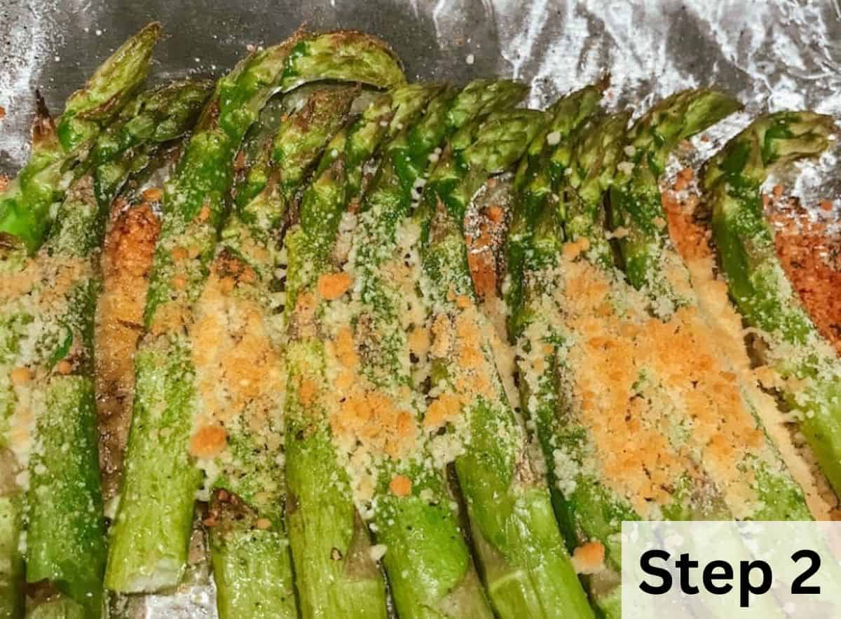 Roasted asparagus laid out on a baking sheet and topped with golden brown parmesan cheese.