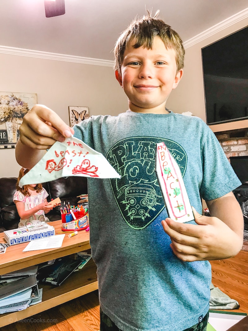 A boy holding the decorated pieces for his model boat.