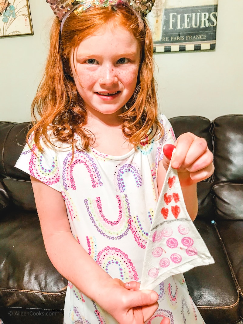 A girl holding her decorated boat sail.