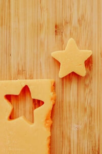 Cheese cut into star shapes on a wooden cutting board.