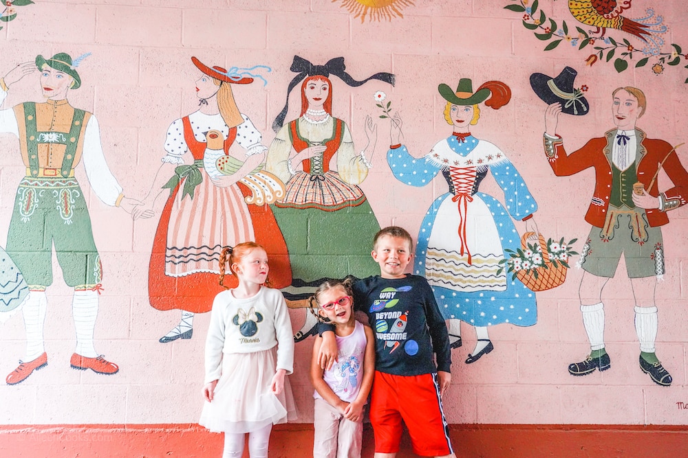 Three kids standing in front of a mural at Hofsas House Hotel.