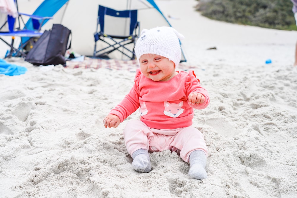 A baby sitting in the sand at Carmel Beach.