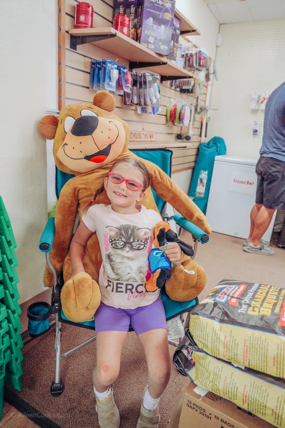 A little girl sitting on a giant stuffed bear. 