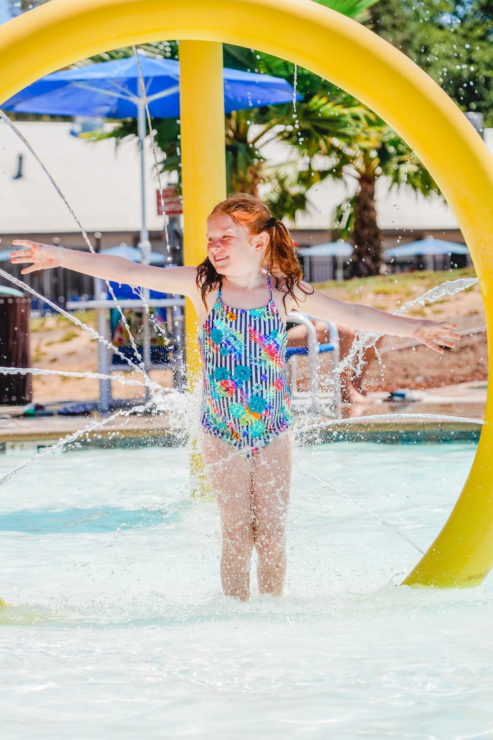 A girl standing inside of a spraying water feature in one of the pools at Tower Park.