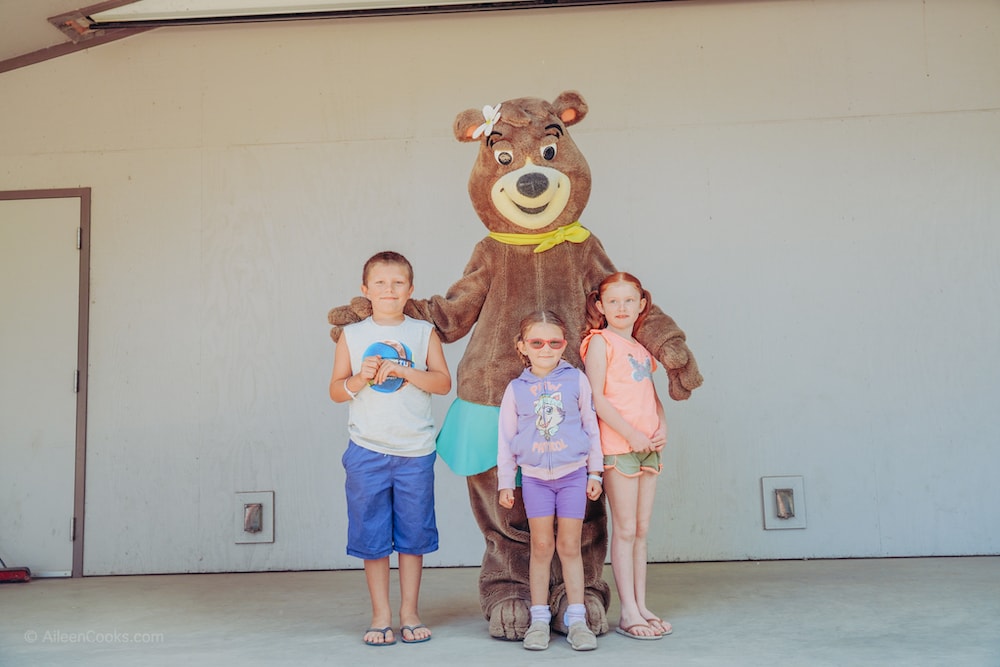 Three kids standing with Cindi Bear at Yogi Bear's Jellystone Park.