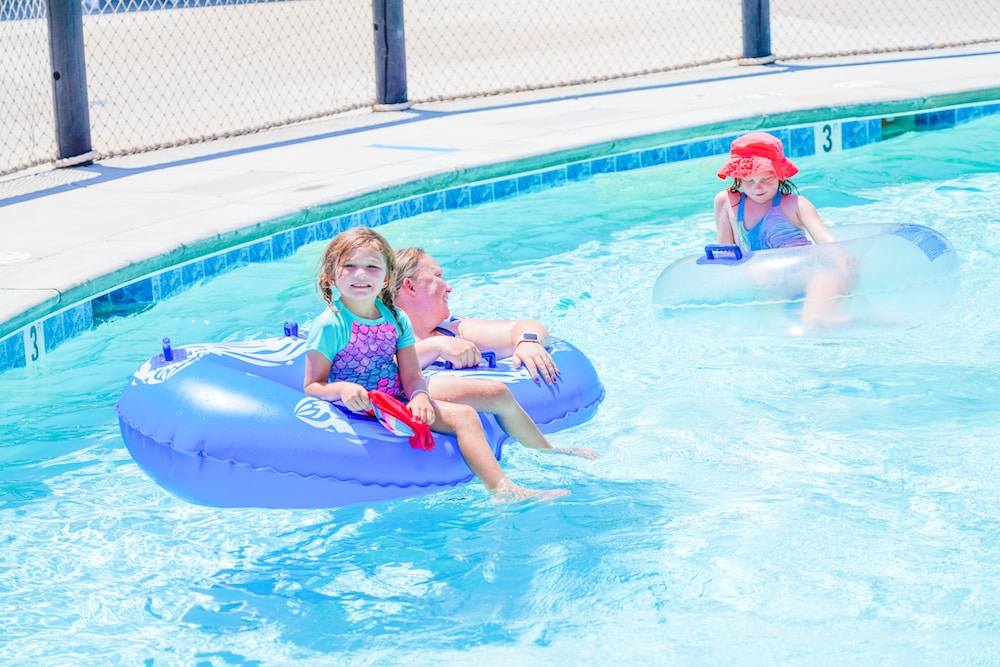 A mom with her two daughters sitting in blue inner tubes on a lazy river.