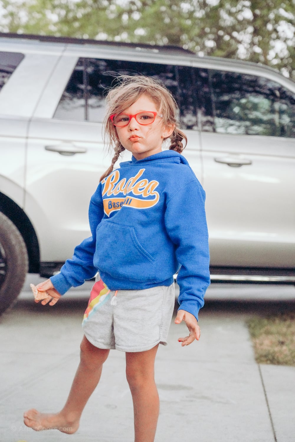 A little girl standing outside and eating a s'more.