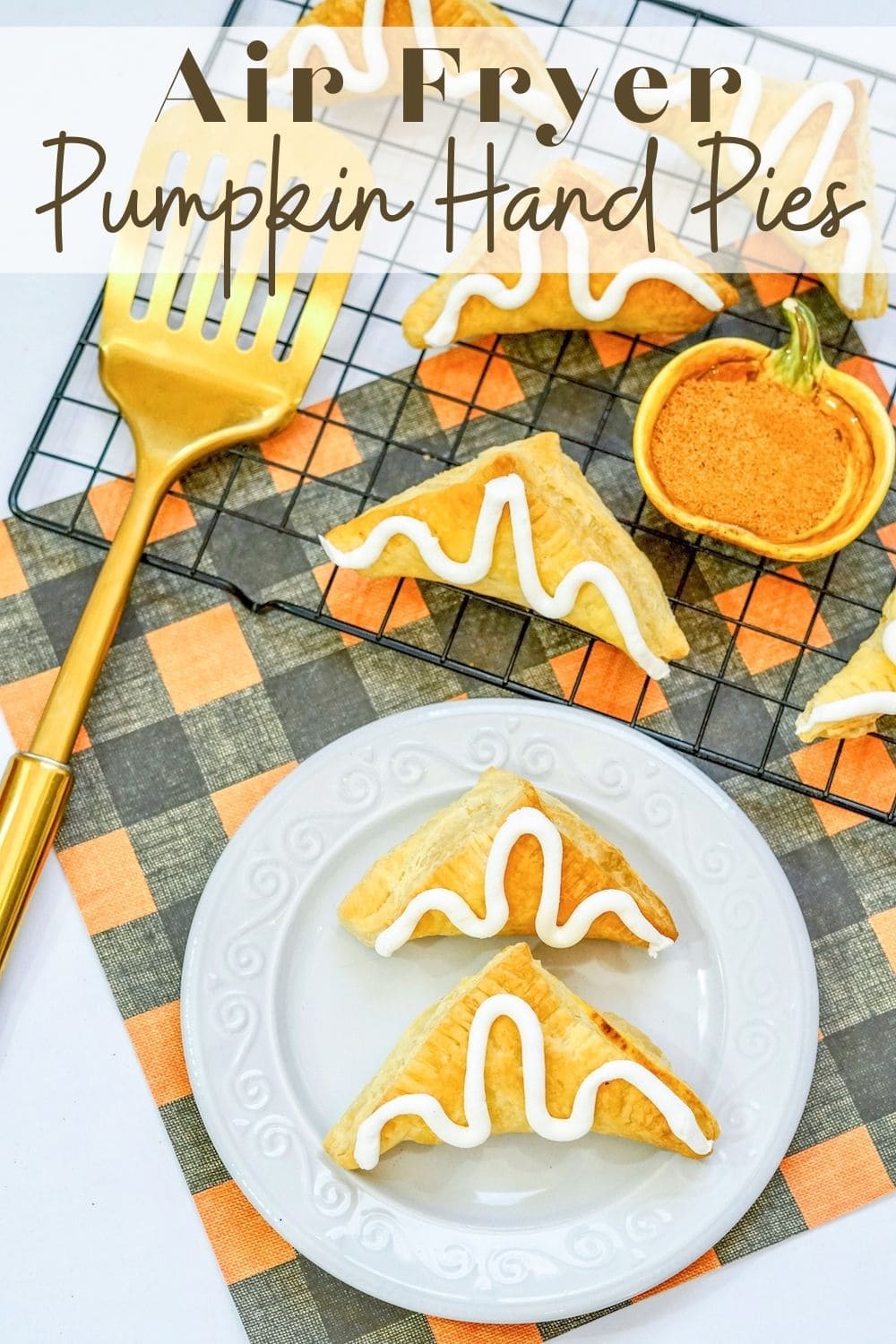 Two pumpkin hand pies on a white plate with the words "Air Fryer Pumpkin Hand Pies" in brown lettering at the top of the image.