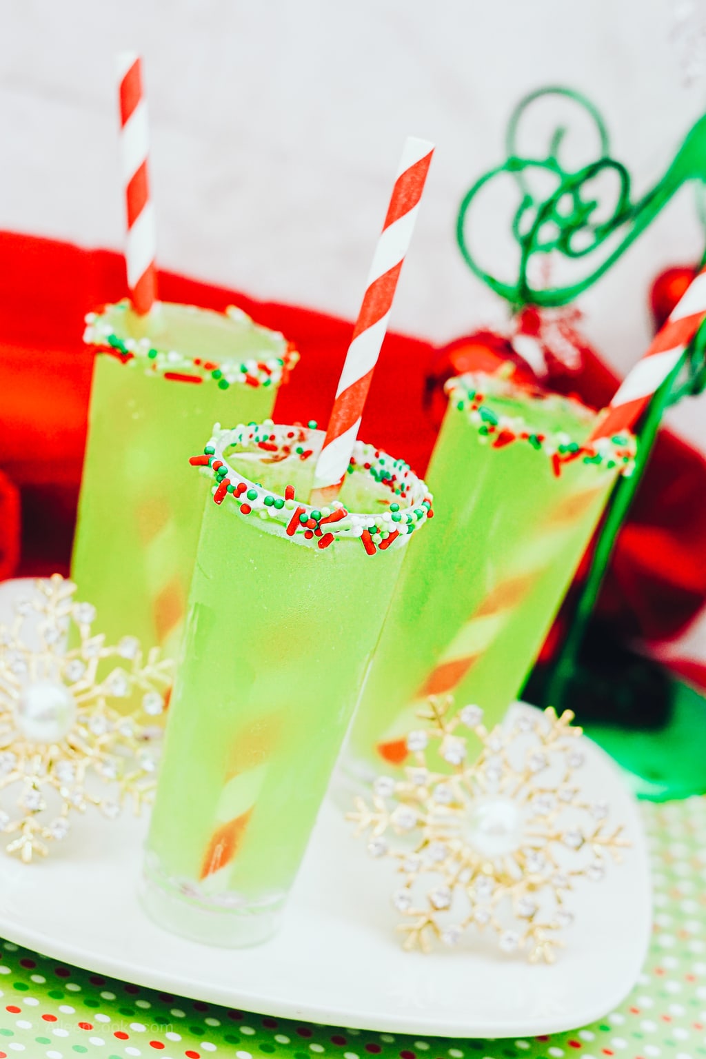 Three green shots with red and white sprinkles on the rim. 