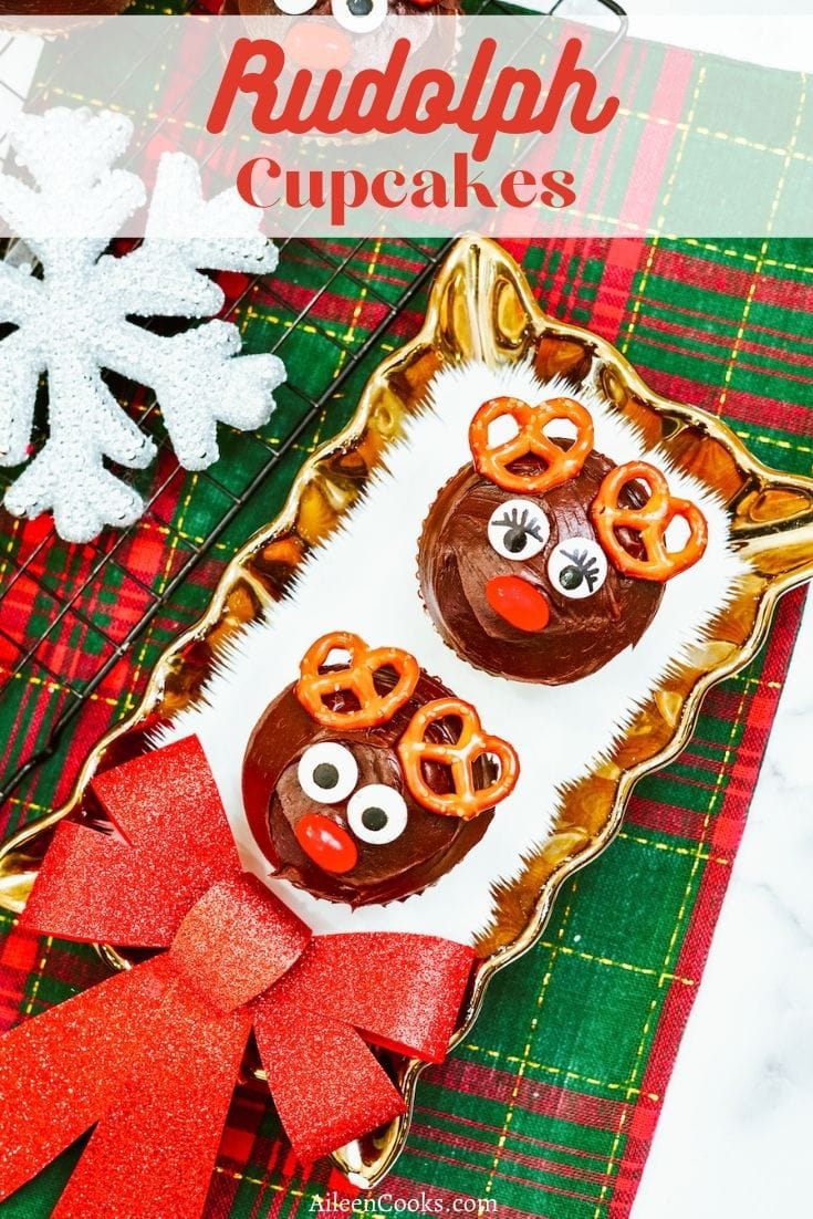 Two Rudolph the red nosed reindeer cupcakes on a gold and white decorative plate.