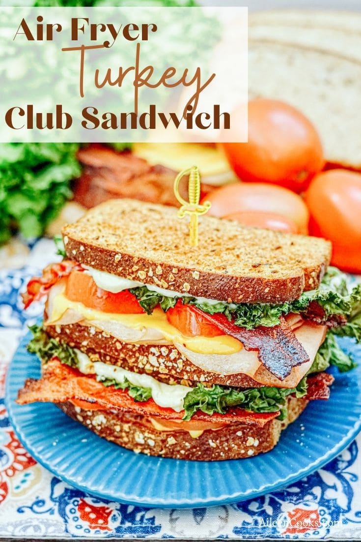 A grilled sandwich on a blue plate with the words "Air Fryer Turkey Club Sandwich" in brown lettering.