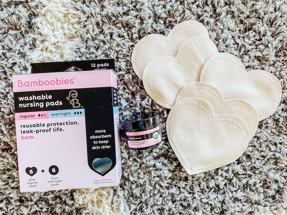 A Bamboobies box and heart shaped nursing pads on a grey rug.