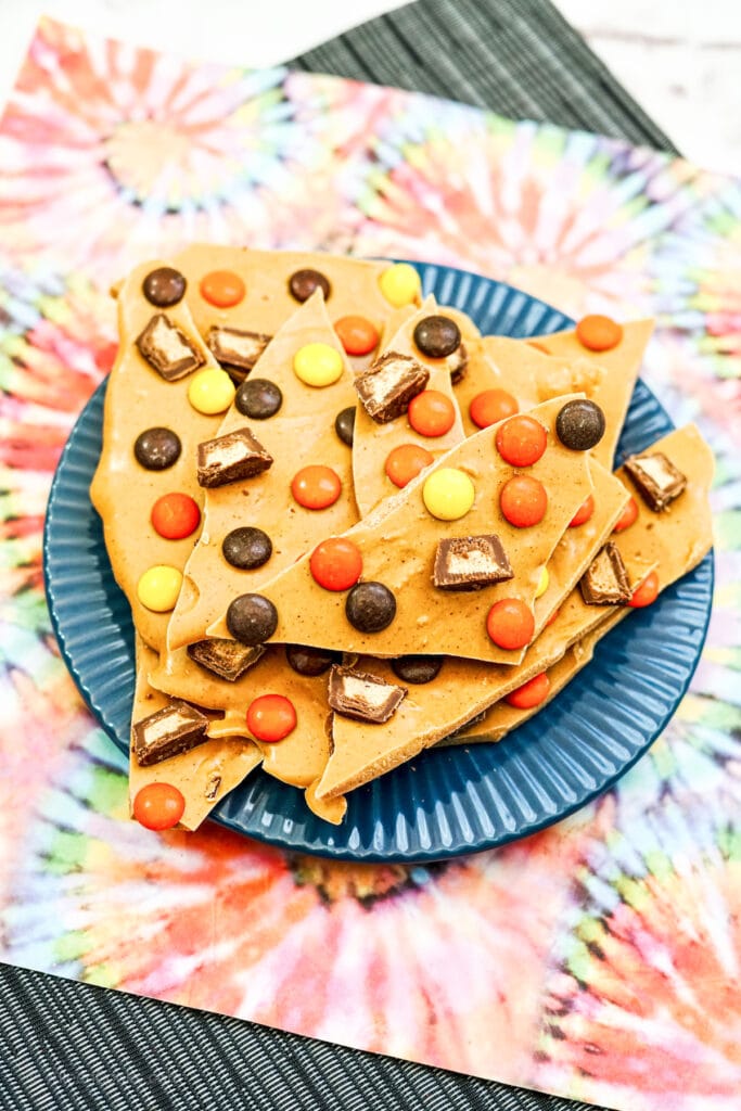 A tie-die placemat under a plate full of peanut butter cup bark candy.