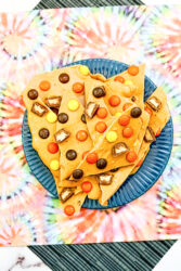 A plate full of Reese's pieces peanut butter bark broken into triangles.