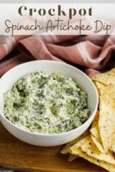 A picture of a bowl of chips and dip with the words "crockpot spinach artichoke dip" in brown lettering.
