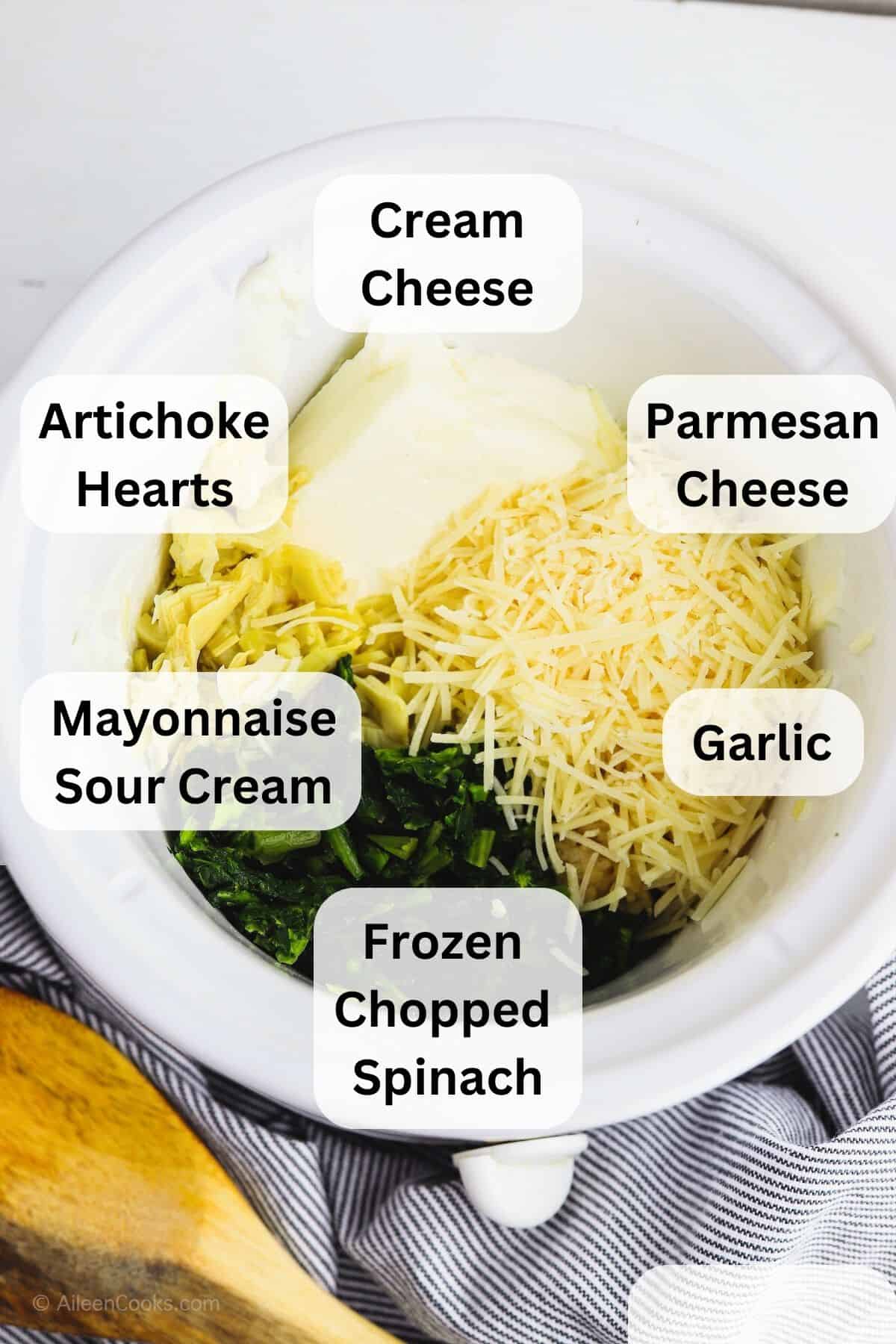 A crockpot filled with ingredients to make spinach artichoke dip.