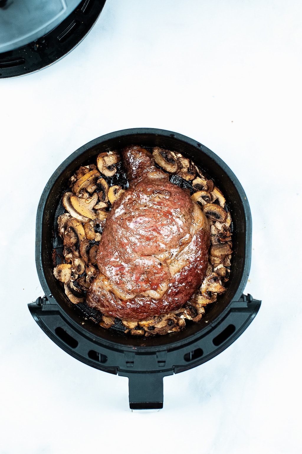 A cooked steak in side of an air fryer basket.