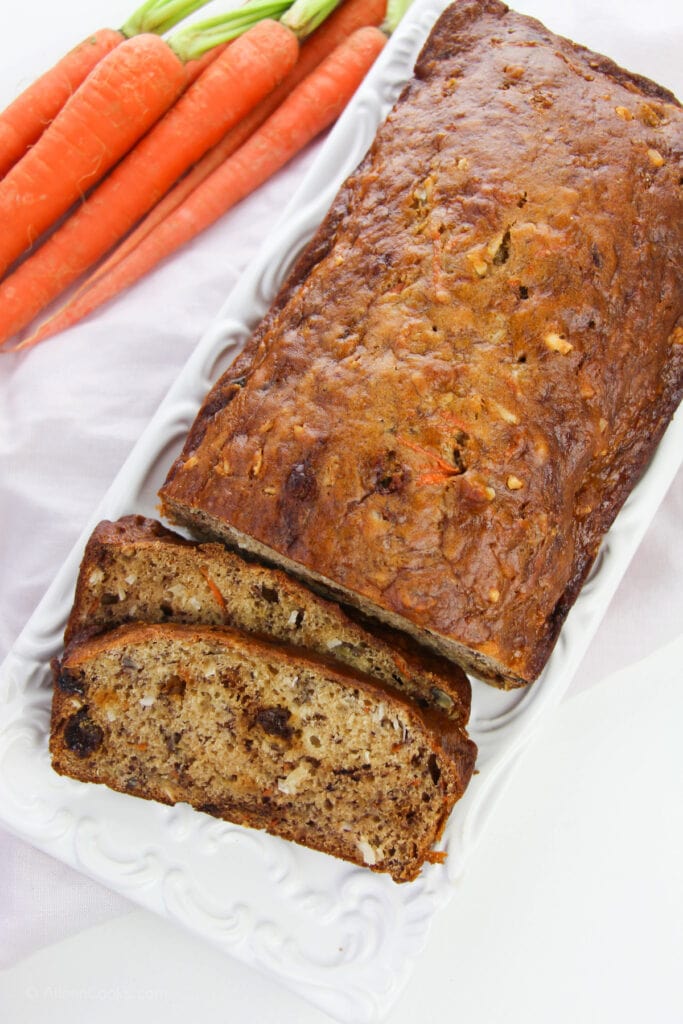 A loaf of carrot bread with two slices cut and leaning on it.