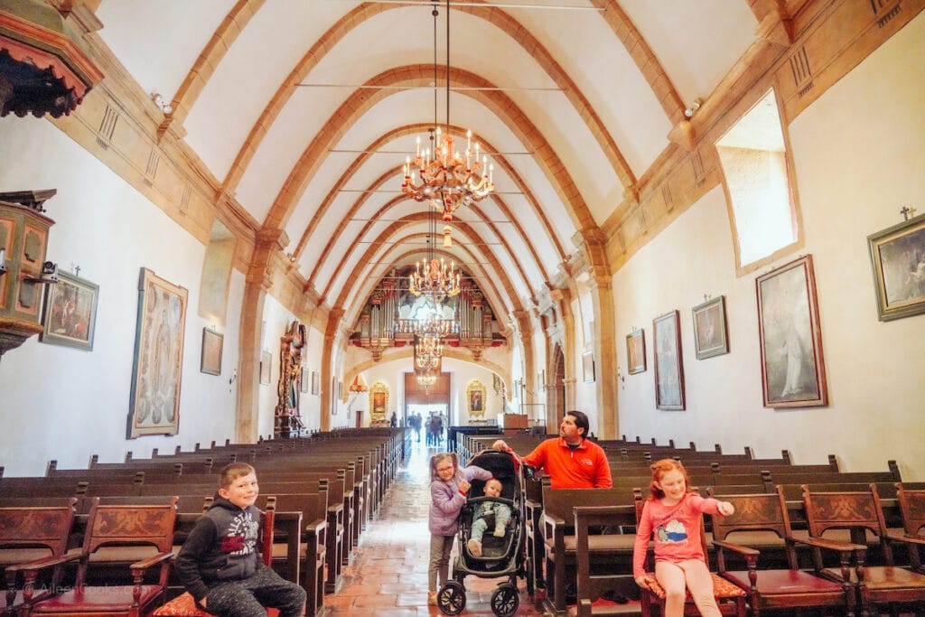 A family sitting inside the chapel of Mission Carmel.