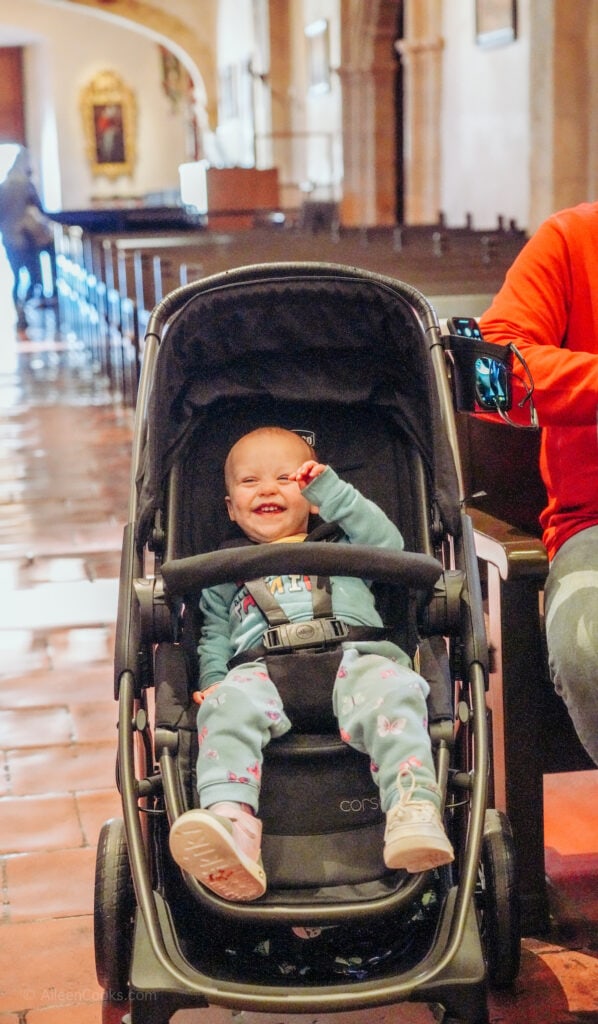 A baby sitting in a stroller and smiling.