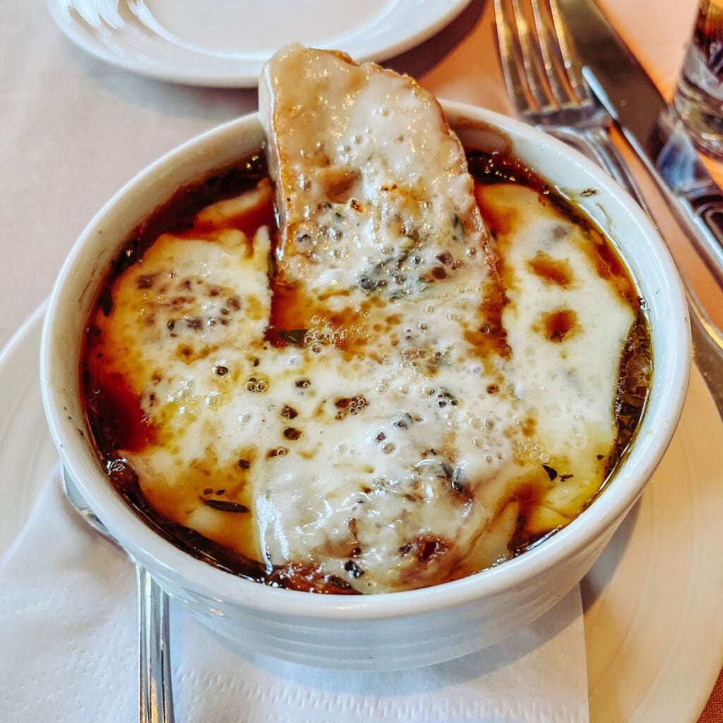 A bowl of French onion soup with a slice of bread on top.