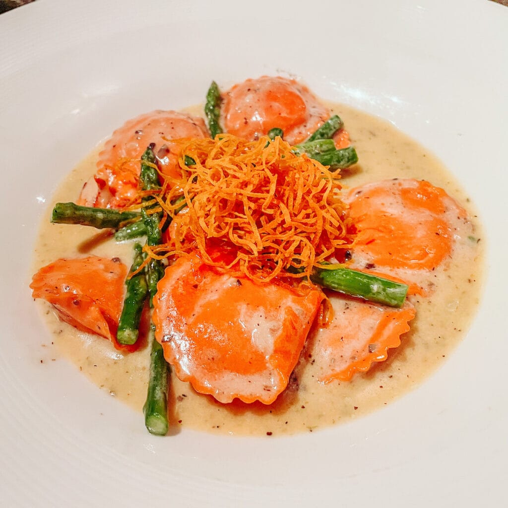 A bowl of lobster ravioli topped with asparagus.