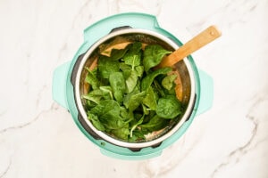 Baby spinach leaves on top of a soup inside an Instant pot.