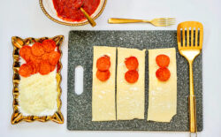 Three puff pastry sheets topped with pizza sauce, cheese, and pepperoni.