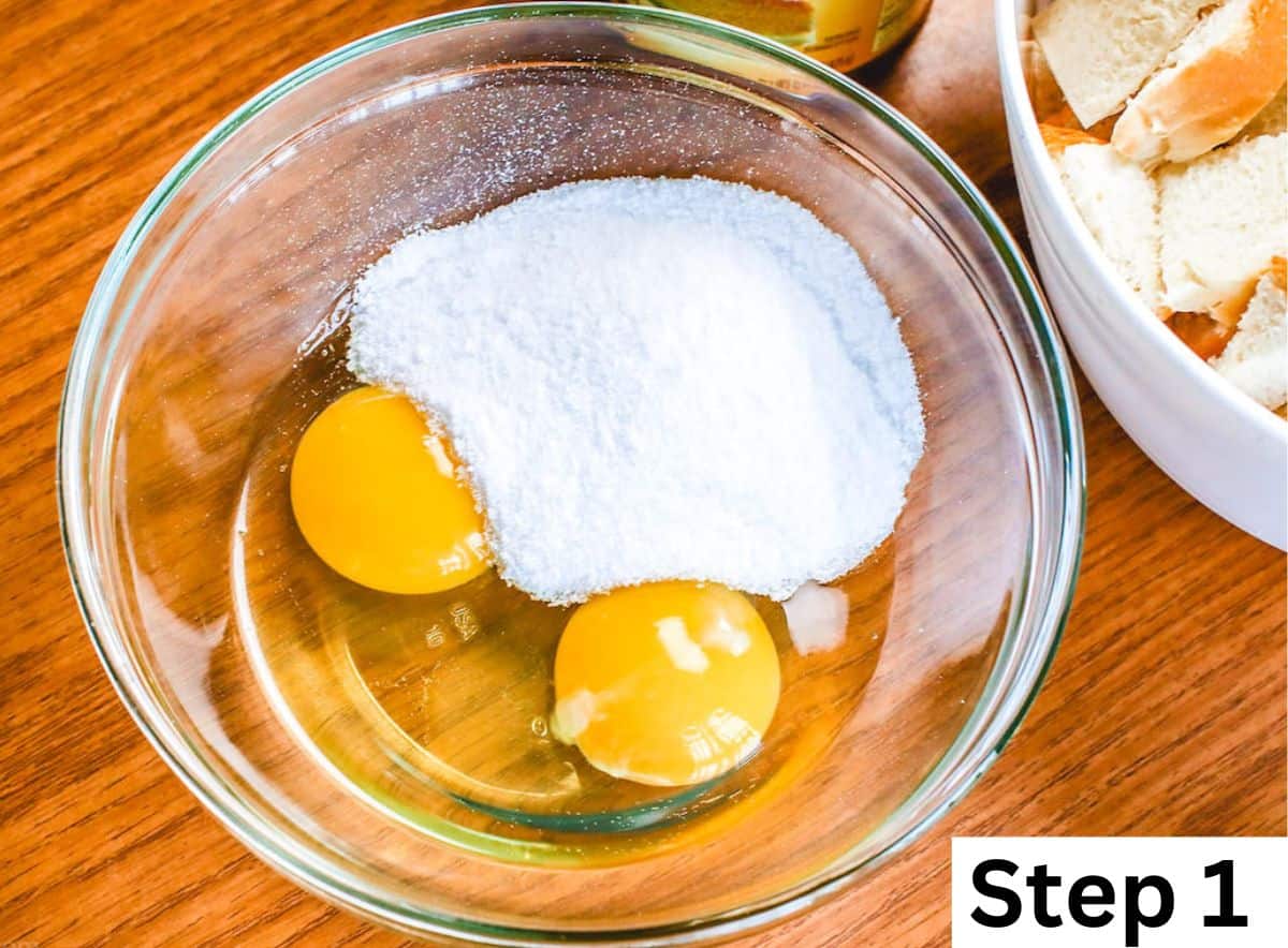 Granulated sugar and two eggs inside a clear glass bowl.