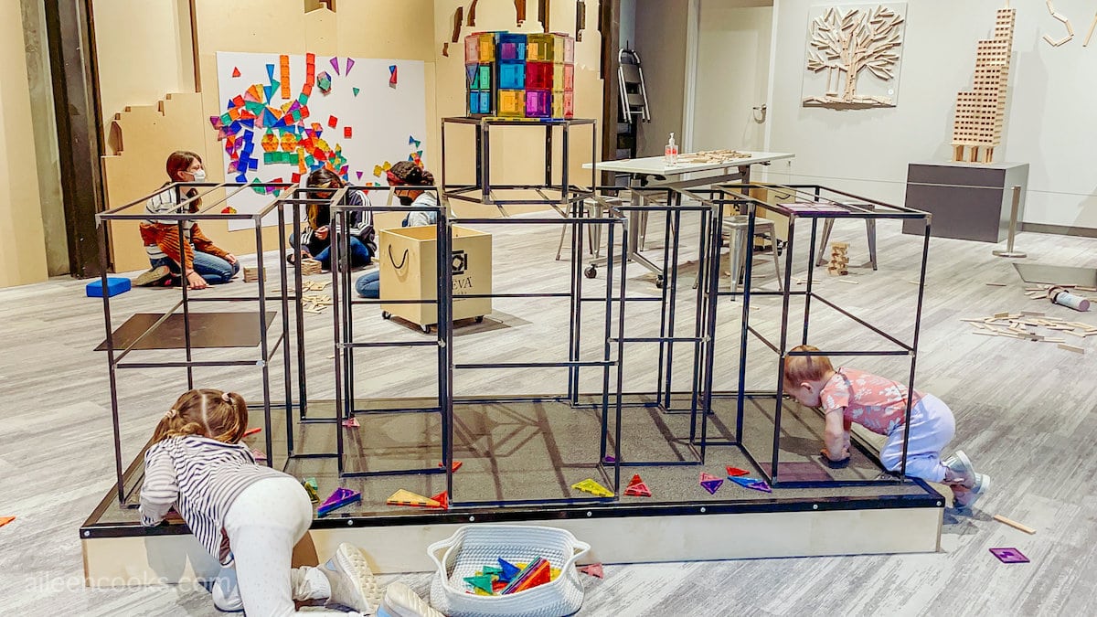 Two children building with magnetic blocks on a metal structure.