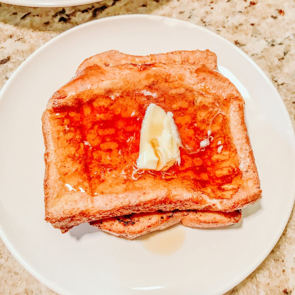 Two slices of French toast topped with butter.
