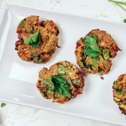 A plate of air fryer salmon cakes, garnished with parsley and on a marble background