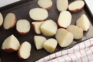 Boiled red potatoes lying on a black sheet pan