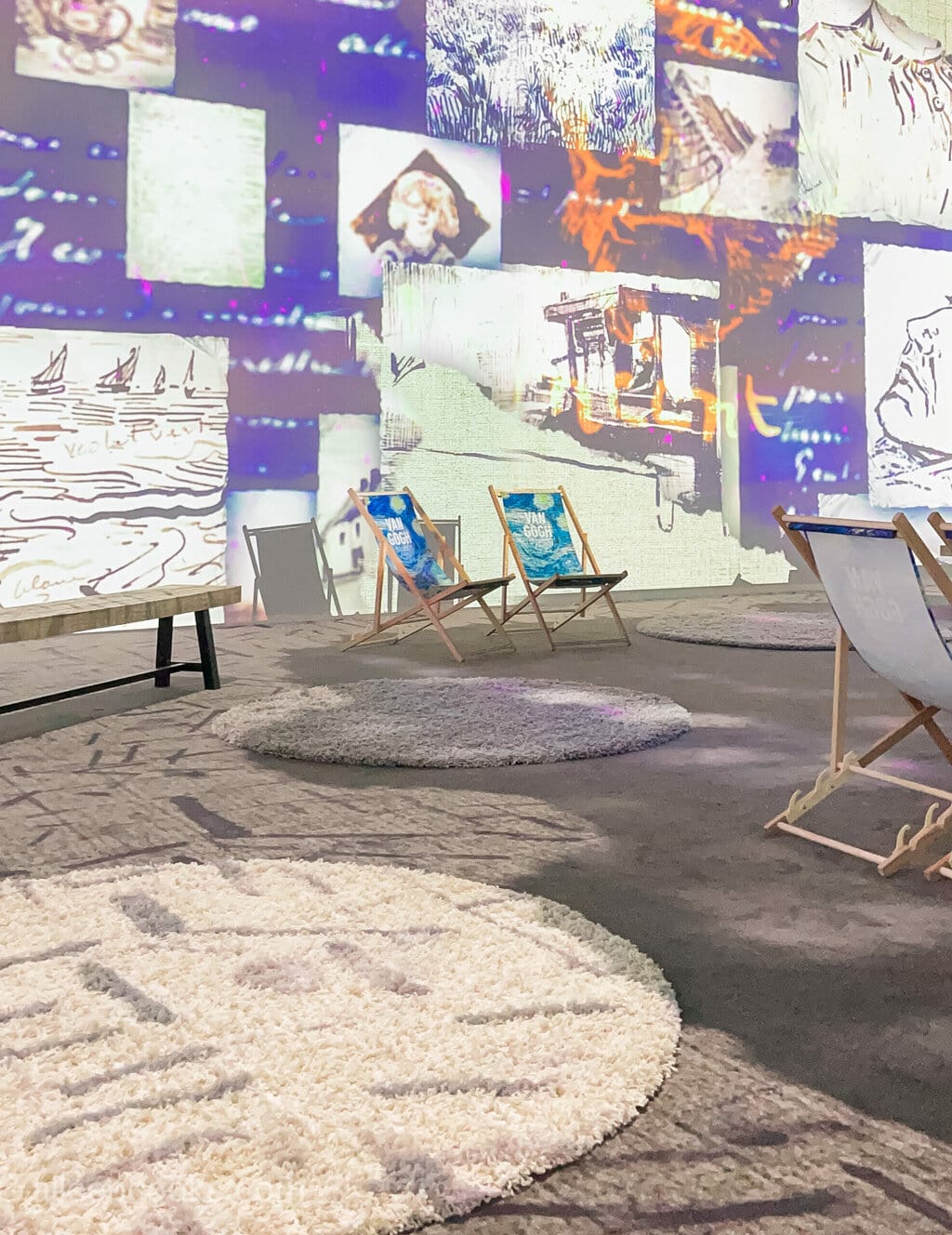 A room with several area rugs and pictures of van Gogh's are projected on the wall in blue colors.